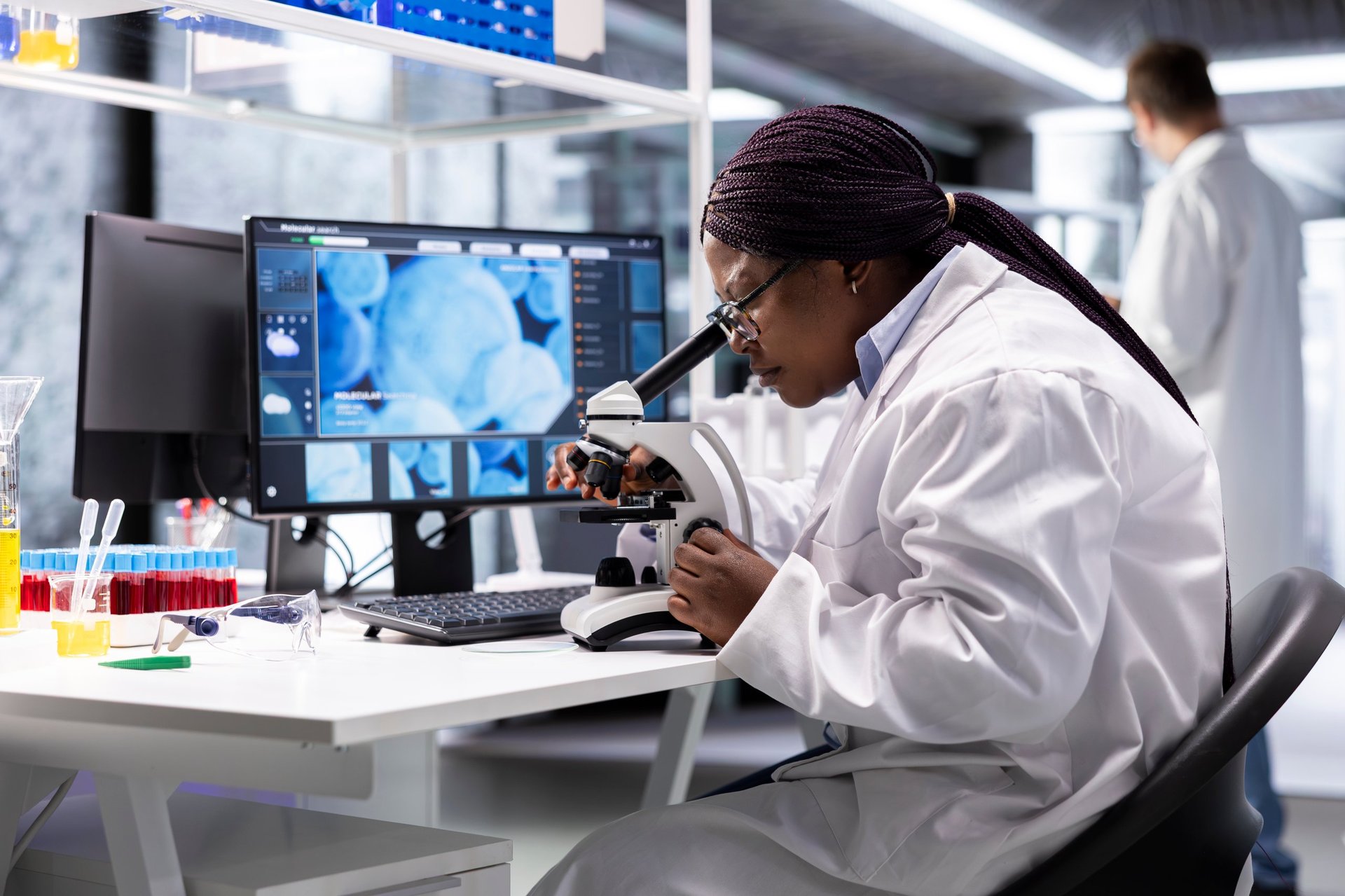 Black scientist examining samples under microscope in a modern laboratory